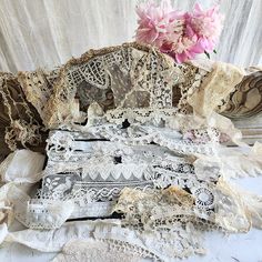 an old chair with lace and flowers on the table next to it is covered in fabric