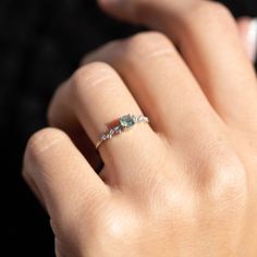 a woman's hand wearing a ring with three stones on the middle of it