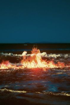 there is a fire in the ocean with waves coming up to it's shore