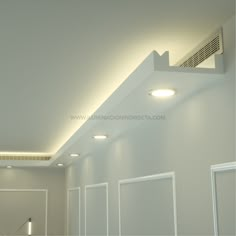 an empty room with white walls and ceiling lights