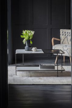 a living room with black walls and white rugs on the floor, two chairs and a coffee table