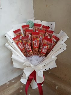 a bouquet of candy wrapped in white paper and tied with a red ribbon on the floor