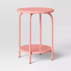 a pink side table with black legs and a round top, on a white background