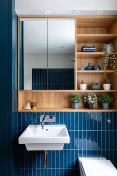 a bathroom with blue tile and wooden shelves on the wall next to a white sink