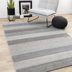 a living room area with a chair, rug and potted plant on the floor