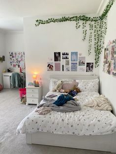 a white bed sitting in a bedroom next to a wall with pictures on it