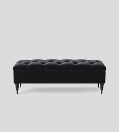 an upholstered black bench with wooden legs