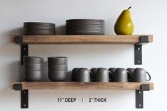 two wooden shelves with plates and cups on them, one has a pear sitting on top