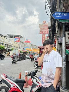 a man standing next to a motorcycle talking on a cell phone while holding his hand up to his ear