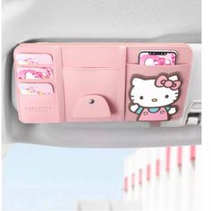 a pink hello kitty cell phone holder hanging from the side of a car