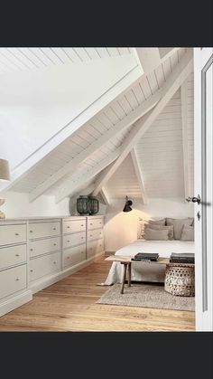 an attic bedroom with wooden floors and white walls, along with lots of storage space