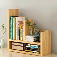 a bookshelf filled with lots of books on top of a wooden floor next to a vase