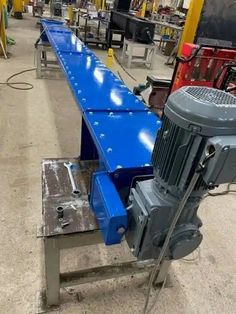 an assembly line in a factory with blue conveyor belt and machine on the side