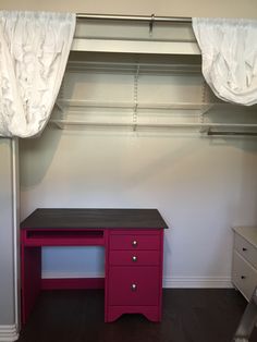 a pink desk in front of a closet with white curtains on the windowsills