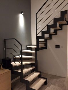 a white and black stair case next to a light on the side of a wall