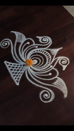 an intricate design on the floor is made with white chalk and orange colored pencils