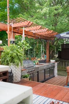 an outdoor kitchen and dining area is shown in this backyard setting with wooden decking