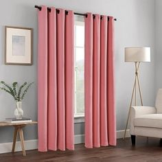 a living room with pink curtains and a white chair