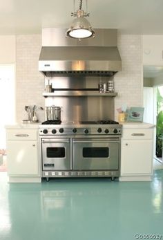 a large kitchen with stainless steel appliances and white cabinets, blue flooring is the focal point in this photo