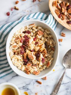 a bowl of oatmeal with pecans and raisins on the side