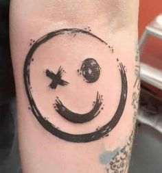 a tattoo with a smiley face on the side of his arm and an arrow in the middle