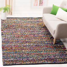 a living room with a white couch and colorful rug on the floor in front of it