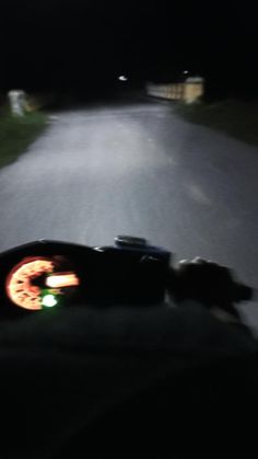 a person riding on the back of a motorcycle down a dark road at night time