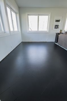 an empty room with black floors and windows