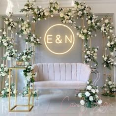 an elegant wedding setup with white flowers and greenery on the wall, along with a gold bench