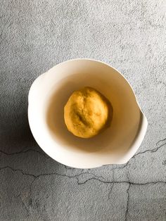 a white bowl filled with food sitting on top of a gray carpeted floor next to a wall