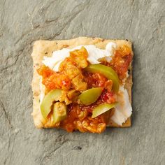 a cracker topped with meat and veggies on top of a stone surface