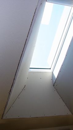 the corner of a room with a skylight in it's center and some dirt on the floor