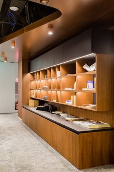 a long wooden shelf filled with lots of books on top of a white floor next to a wall