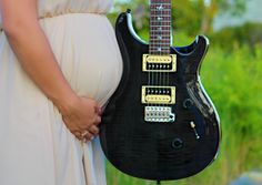 a pregnant woman holding a black electric guitar