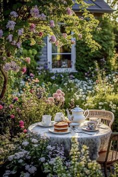 a table with two tea cups and plates on it in the middle of a garden