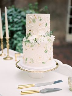 a wedding cake sitting on top of a white table next to candles and other decorations