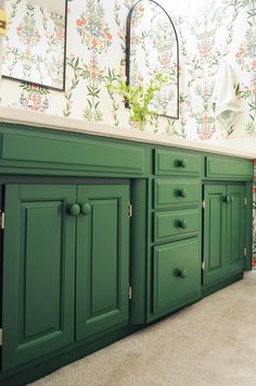 a bathroom with green cabinetry and floral wallpaper