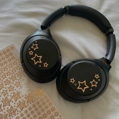 two black headphones with gold stars on them sitting on top of a white sheet