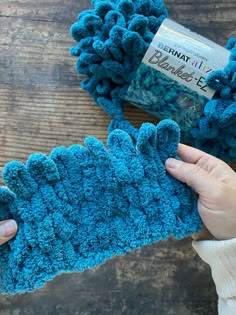 someone is crocheting some blue yarn on a wooden table