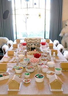 a table is set up for a holiday party with gingerbread houses, candy and marshmallows