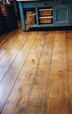 a wooden floor with baskets on it and a cabinet in the back ground behind it