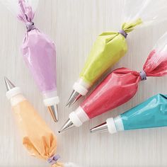 four different colored plastic bottles with metal tip pens in them on a white table top