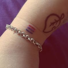 a woman's arm with a tattoo on the wrist and a chain attached to it