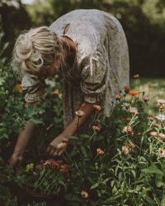 a woman is picking flowers in the grass