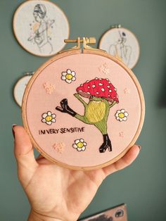 a person holding up a small embroidery project