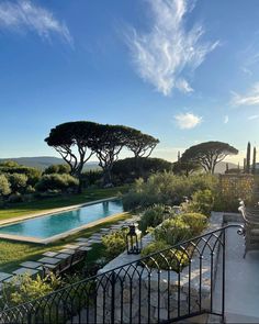 an outdoor swimming pool surrounded by trees and shrubs with the sun shining on it's horizon