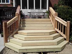 a wooden deck with steps and railings in front of a house