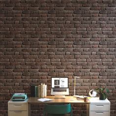 a desk with a computer, keyboard and two drawers in front of a brick wall