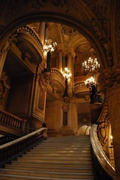 an ornate staircase with chandeliers and lights in a building that looks like a palace