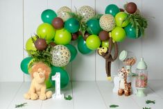 a jungle themed birthday party with green balloons and animal figurines on the table